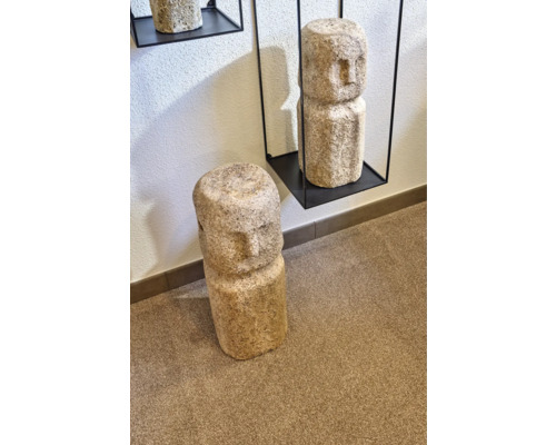 Dekorative Steinskulpturen mit Gesichtern, eine auf einem Regal