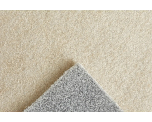 Nahaufnahme eines Nadelfilz-Teppichbodens in Hellbeige mit umgeschlagener grauer Ecke, weiche Oberflächenstruktur.