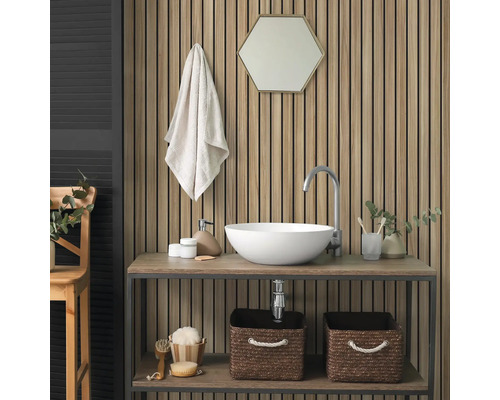 Akustikpaneel mit Holzlamellen an einer Badezimmerwand hinter einem Waschtisch mit weißem Aufsatzbecken und sechseckigem Spiegel.