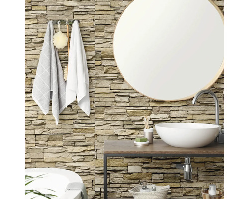 Badezimmer mit Wandverkleidung in Natursteinoptik, rundem Spiegel, hölzernem Waschtisch und weißem Aufsatzbecken.
