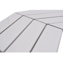 Detailaufnahme von rechteckigen, weißen Keramikfliesen, die in einem Fischgrätenmuster verlegt sind.