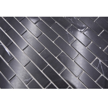 Rechteckige Mosaikfliesen aus Naturstein, verlegt im Fischgrätmuster.