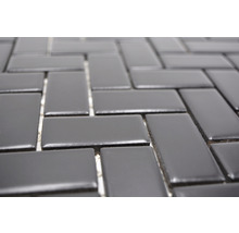 Nahaufnahme eines Mosaiks aus rechteckigen Fliesen, die im Fischgrätmuster angeordnet sind.