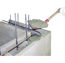 Beton wird mit einer Schaufel in einen Schalungsstein gefüllt.