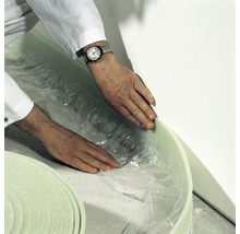 Eine Person rollt Trittschalldämmung aus