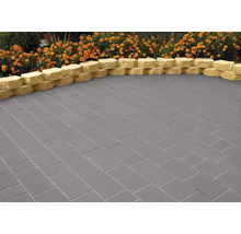 Verlegter grauer Pflasterbelag mit gelbem Rand und Blumenbeet