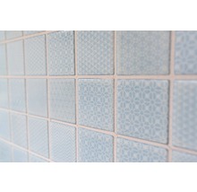 Nahaufnahme von hellblauen, quadratischen Wandfliesen mit verschiedenen Mustern