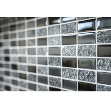 Nahaufnahme einer Mosaikfliesenwand mit abwechselnd glänzenden und steinartigen Oberflächen