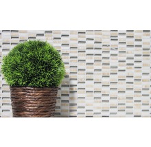 Dekorative Kunstpflanze im Topf vor Mosaikhintergrund