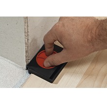 Person verwendet ein Einstellwerkzeug für Paneele an der Wand