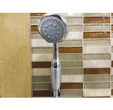 Handbrause aus Metall vor einem Badezimmerhintergrund.