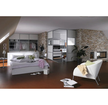 Helles Schlafzimmer mit Bett, Kleiderschrank, Badezimmer und Backsteinmauer