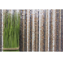 Dekorative grüne Kunstpflanze vor einer Mosaikwand aus Glas