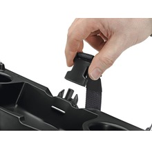 Person befestigt einen Gurt an einem schwarzen Behälter.