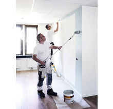 Zwei Handwerker streichen einen Raum mit Farbroller und Pinsel