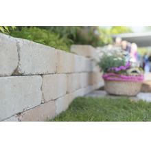 Mauer aus Mauersteinen im Garten mit Dekoration.