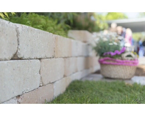 Mauer aus Mauersteinen im Garten mit Dekoration.
