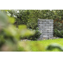 Gemauerte Gartensäule aus Steinblöcken neben einem Rasen