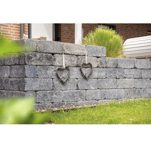 Graue Gartenmauer aus Betonsteinen mit zwei Herzdekorationen