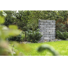 Landschaftsbild mit Mauerwerk aus Steinblöcken und Metallzaun im Garten