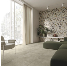 Heller Wohnraum mit Fliesenboden, Fenster, Vorhang, Sessel, modularem Sofa und Wandtapete mit Pflanzenmuster.