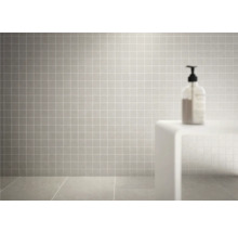 Quadratische, graue Fliesen an Wand und Boden eines Badezimmers.