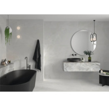 Helles Badezimmer mit freistehender Badewanne, Waschtisch und rundem Spiegel