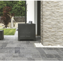 Terrasse mit Pflastersteinen und Wandverkleidung in Steinoptik sowie Sitzmöbeln