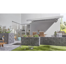 Außenbereich mit Steinmauern, Markise, Gartenmöbeln und Boulekugeln auf Rasen