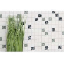 Dekorative Kunstpflanze vor einer Wand mit kleinen Mosaikfliesen