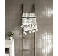 Dekorative Holzleiter mit gestreifter Decke mit Quasten an einer gefliesten Wand