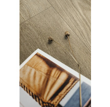 Nahaufnahme von Laminatboden mit Dekor und zwei getrockneten Blüten