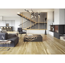 Heller Wohnraum mit Treppe, Sitzmöbeln, Couchtisch und Kamin.