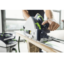 Mann sägt Holzbrett mit einer Festool Tauchsäge auf einer Führungsschiene, mit einem Staubsauger im Hintergrund