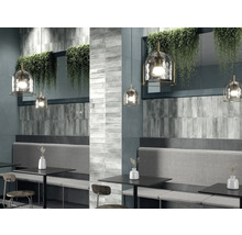 Innenraum mit grau gefliesten Wänden, Sitzbänken und Pendelleuchten