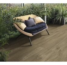 Terrasse mit Holzoptik Fliesen und Rattansessel im Garten.