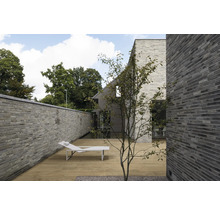 Außenbereich mit Holzterrasse, Mauer und Liegestuhl