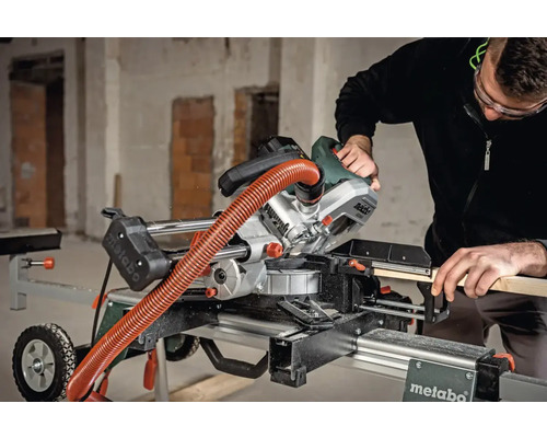 Eine Person bedient eine Metabo Kapp- und Gehrungssäge auf einem Arbeitstisch.