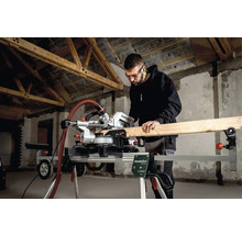 Mann mit Schutzbrille sägt Holz mit einer Metabo Kappsäge auf einem Untergestell in einem Rohbau.