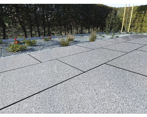 Terrasse mit grauen Steinplatten und Kiesbeet mit Pflanzen