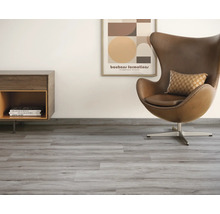 Wohnzimmer mit grauem Vinylboden, Sessel, Kommode und Wandbild