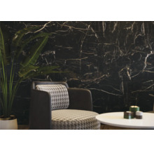 Wohnzimmer mit schwarzer Marmorwand, Sessel und Tisch