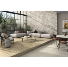 Heller Wohnraum mit Fliesenboden in Holzoptik, grauer Wandfliese und Sitzmöbeln