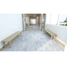 Heller Raum mit Bänken, Bücherregalen und grauem Fliesenboden.