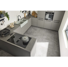 Helle Küche mit Einbauschränken, Spüle, Kochfeld und Fliesenboden.