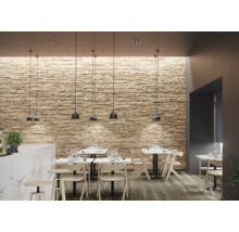 Innenraum mit Wandverkleidung in Steinoptik, Pendelleuchten und Tischen mit Stühlen.