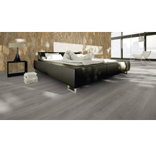 Schlafzimmer mit Doppelbett, Nachttischlampe und grauem Holzboden