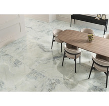 Heller Raum mit Fliesen in Marmoroptik, Esstisch und Stühlen.