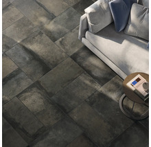 Boden mit dunklen Fliesen in Steinoptik, verlegt im Fischgrätenmuster, Sofa und Beistelltisch