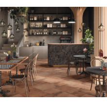 Gastronomiebereich mit Tischen, Stühlen, Bar und terracottafarbenen Bodenfliesen für ein rustikales Ambiente.